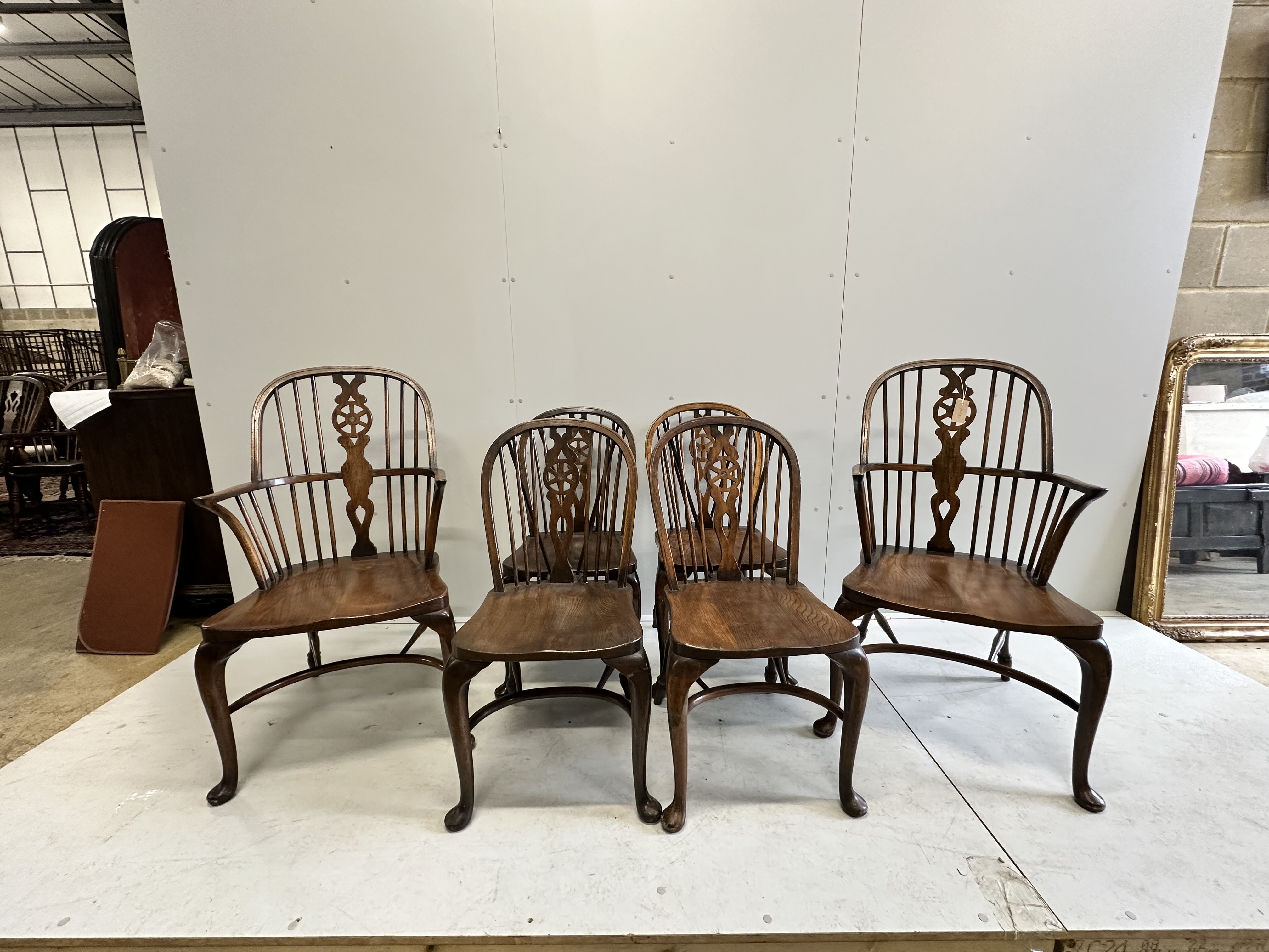 A set of six reproduction elm and beech Windsor wheel back dining chairs on cabriole legs with crinoline stretchers, two with arms